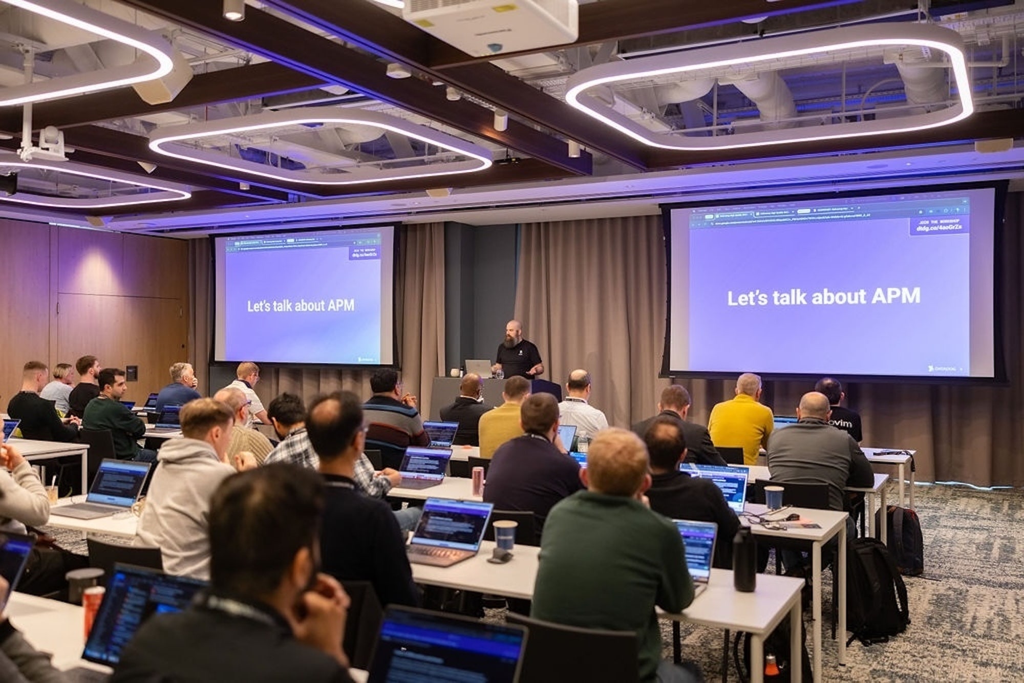 A presenter leads a workshop in a room full of attendees at Datadog Summit.
