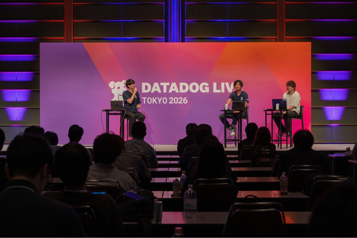 Datadog Live Tokyo 2026 のステージに座って Fireside Chat に参加する木村健人、石垣雅基、若原義隆。 Datadog Live Tokyo 2026 のステージに座って Fireside Chat に参加する木村健人、石垣雅基、若原義隆。